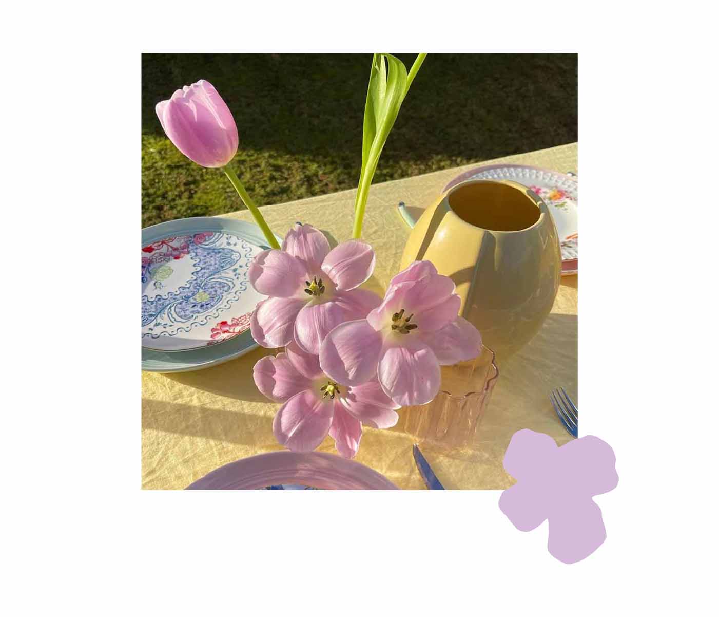 Bud vase with pink flowers on table with pastel yellow tablecloth
