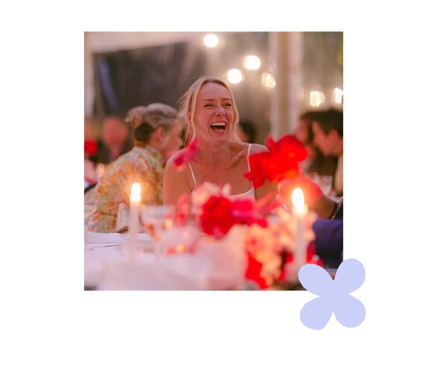 Woman laughing at table decorated with red flowers