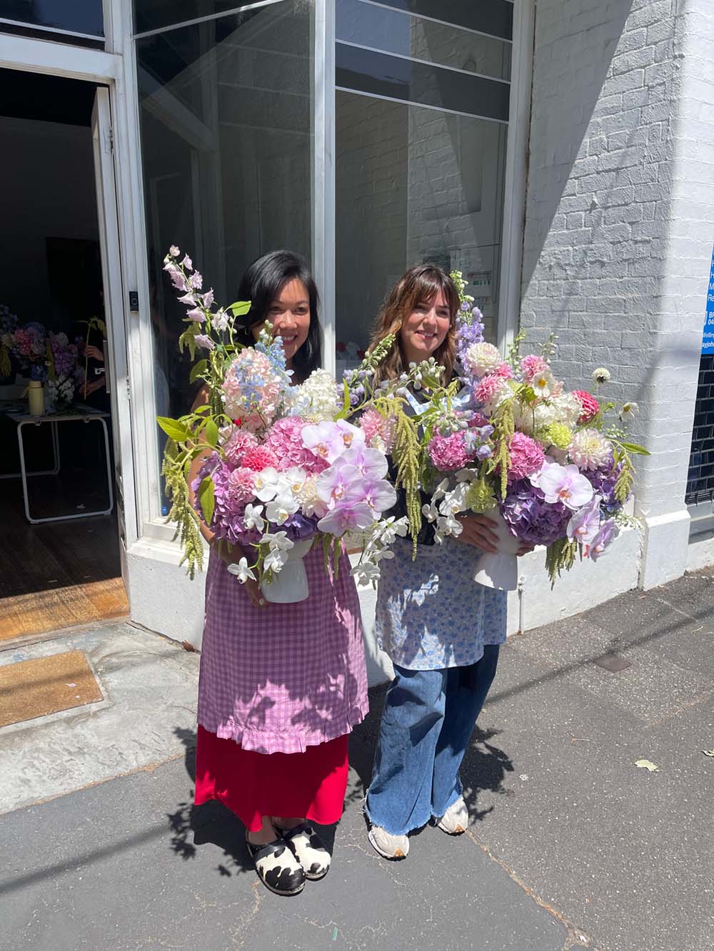 Two women holding flower bouquets on a street