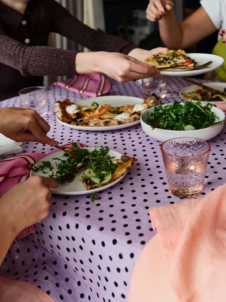 Dinner party with people eating and lilac dot tablecloth by Mosey Me